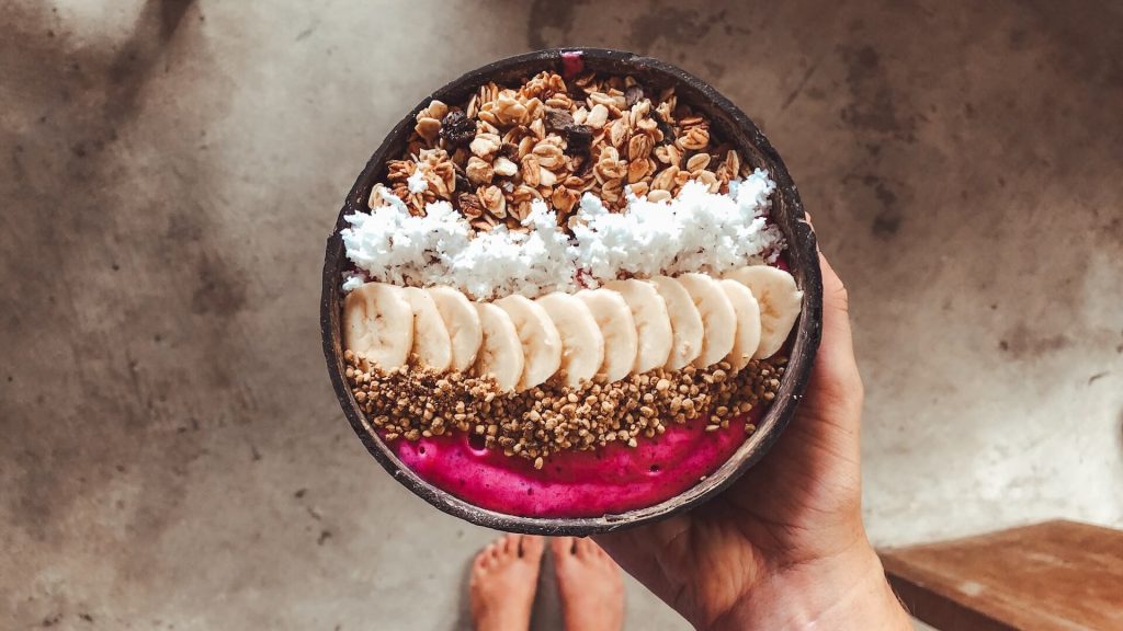 A smoothie bowl with bananas, coconut, granola and nuts on top